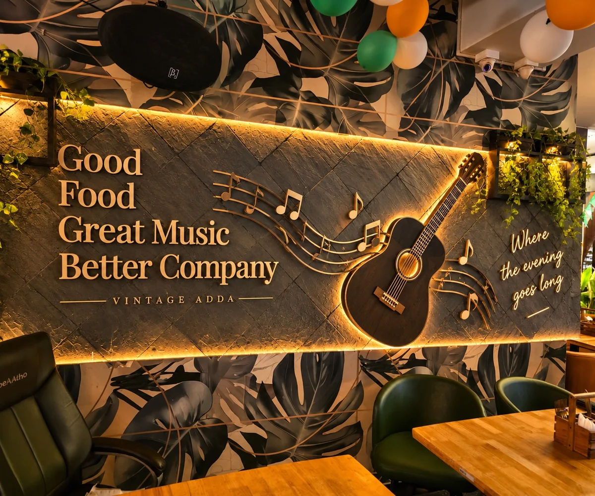 The backlit lyric wall, with Good Food, Great Music, Better Company in brass on slate, and a guitar and a run of music notes beside it.